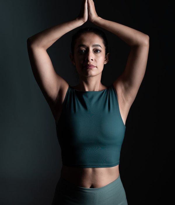 Woman performing a calm yoga pose in a dark room with green light.